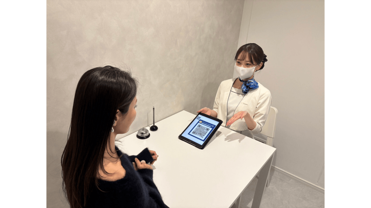 ストラッシュの受付スタッフがタブレットのQRコードを案内する実際の写真