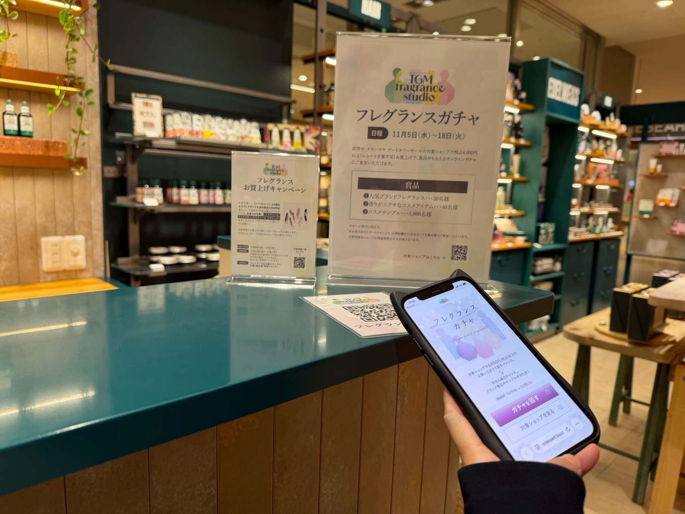 タカシマヤ ゲートタワーモールの店頭で、フレグランスガチャをスマートフォンに表示している実際の写真